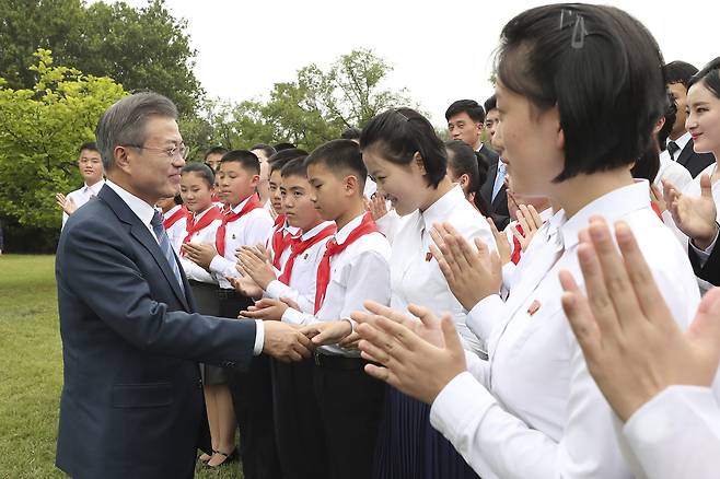 문재인 대통령이 19일 오후 남북정상회담 숙소로 사용한 평양 백화원초대소에 남쪽에서 가져온 10년생 모감주나무를 심은 뒤 행사에 참석한 북측 학생들과 인사하고 있다. 평양사진공동취재단