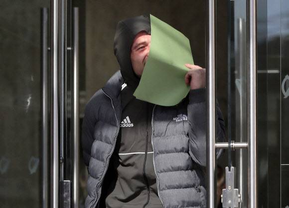 탑승 수속에 지각한 여객기에 오르겠다고 활주로를 내달린 아일랜드 청년 패트릭 케호가 27일(현지시간) 더블린 형사법원에서 열린 재판을 마친 뒤 나오다 서류로 얼굴을 가리고 있다.　더블린 AP 연합뉴스