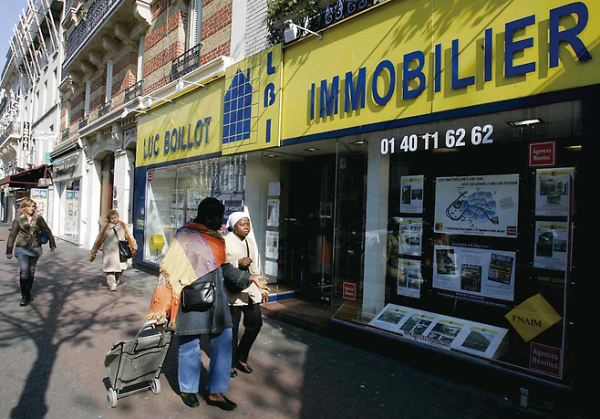 프랑스 파리 시내에 위치한 부동산 중개업소 앞을 지나가던 한 시민이 창문에 붙은 집값 정보를 살펴보고 있다. © AP 연합