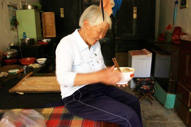 동굴집에 앉아 식사를 하는 할머니.