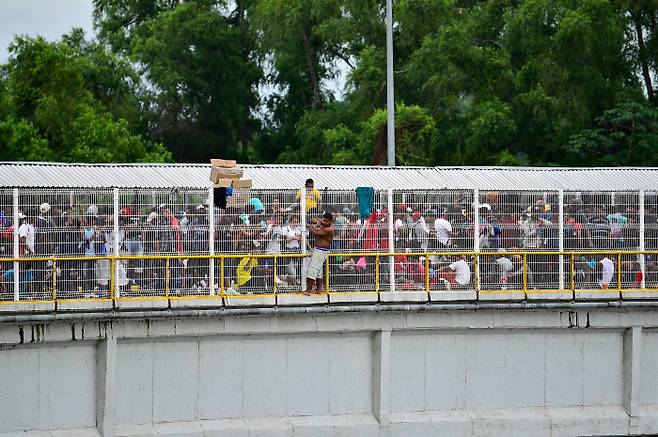 수치아떼 강 위 다리에 위태롭게 매달린 온두라스 이민자.  AFP=연합뉴스