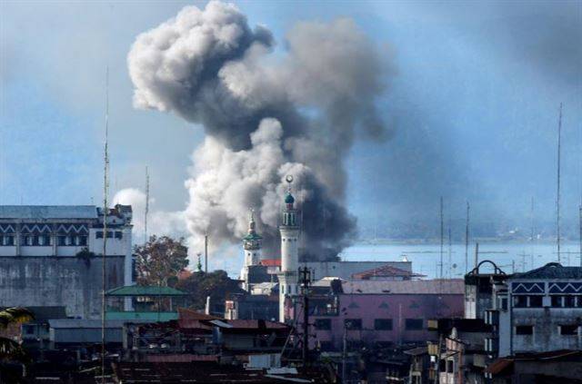 필리핀 민다나오섬의 도시 마라위에서 이슬람국가(IS) 추종 무장반군 ‘마우테그룹’과 정부군 간 교전이 한창 진행 중이던 지난해 6월 27일, 정부군이 공습을 가한 지점에서 연기가 피어 오르고 있다. 지난해 5월 말 시작된 이 전투는 5개월 후 정부군의 승리로 끝났으나, 사상자 3,000여명이 발생했고 이슬람 문화유산으로 가득했던 도시는 폐허가 됐다. 민다나오=로이터 연합뉴스