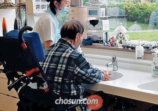 휠체어 들어가는 세면대 - 휠체어를 탄 한 일본 노인이 요양보호사의 도움으로 손을 씻고 있다. 일본은 고령자 주택을 고쳐 휠체어를 타고도 싱크대·세면대·화장실을 쓸 수 있도록 하고 있다. /김철중 의학전문기자