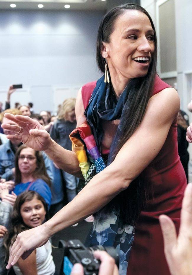 지난 6일(현지 시각) 열린 미국 중간선거에서 미 최초의 여성 원주민 하원의원이 된 샤리스 데이비스가 당선 결과가 발표된 뒤 지지자들과 환호하고 있다. 과거 고위직에 진출한 미국 여성들은 대체로 노출이 적은 정장 차림을 입었지만, 데이비스는 이날 성소수자임을 상징하는 무지개색 스카프와 격투기 훈련으로 다져진 팔 근육이 드러나는 타이트한 민소매 원피스 차림으로 공식 석상에 나섰다. /게티이미지코리아