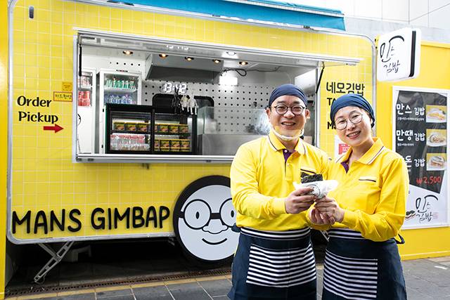 노란 단무지를 연상시키는 노란 타일로 단장한 푸드트레일러 가게 ‘만스김밥’ 앞에 선 김상만 대표와 아내 박민영 씨. 두 사람은 “만스김밥이 간단하지만 맛나고 든든한 한 끼가 되길 바란다”고 입을 모았다. 소상공인시장진흥공단 제공