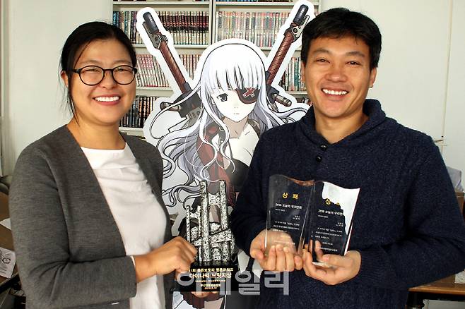 ‘심해수’로 ‘2018 오늘의 우리만화상’을 수상한 노미영(왼쪽) 이경탁 작가가 상을 들고 포즈를 취하고 있다. (사진=투믹스)