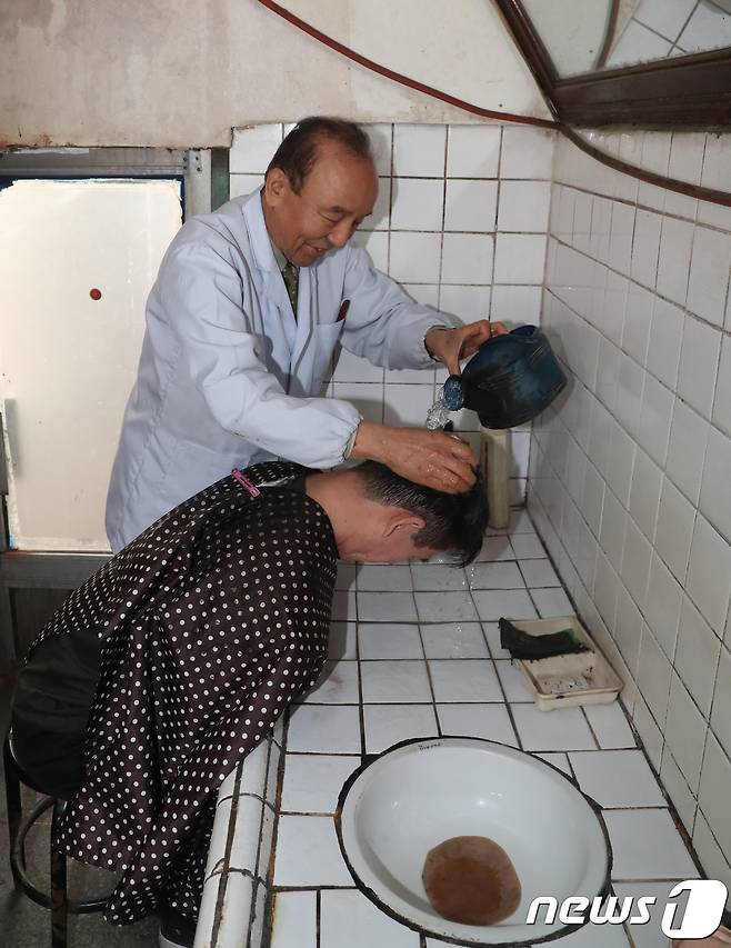 대전 동구 소제동 문을 연지 50여년 된 대창미용원 이종완 이발사(82)가 이발을 마친 손님의 머리를 감고 있다. 이 씨는 “10여 년 전부터 재개발 얘기가 나와서 개발이 시작되면 나도 가위를 놓아야지 싶었다. 그렇게 하루하루 기다리다 보니 어느덧 80이 넘어서도 가위를 놓지 못하고 있다”고 말했다. 2019.1.4/뉴스1 © News1 주기철 기자