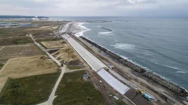 바닷물 유입을 막기 위해 콘크리트 구조물이 태평양 해안을 따라 새로 세워졌다. 멀리 집들이 보이는 마을은 후쿠시마 제1원전에서 북쪽 10㎞가량 떨어진 나미에 지역이다. 수증기가 나오는 건물은 핵쓰레기 소각공장이다. 그린피스 제공
