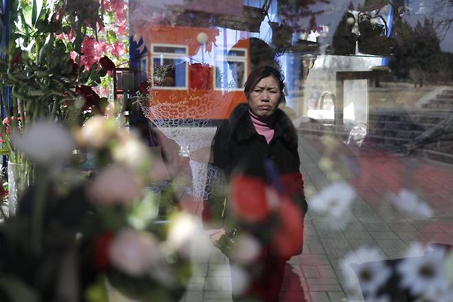 한 평양 여성이 '국제부녀절'을 맞아 선물용 꽃다발을 마련한 꽃집 앞을 지나가고 있다. [AP=연합뉴스]