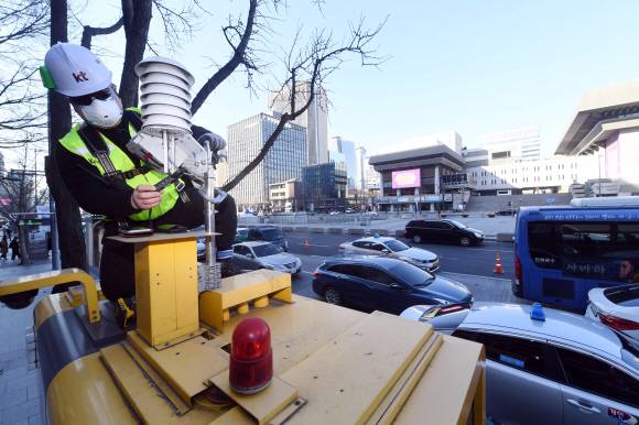 서울 광화문에서 Kt 직원이 공중전화부스 위에 미세먼지를 측정하기 위해 설치한 공기질측정기를 점검하고 있다. 2019. 3. 7 정연호 기자 tpgod@seoul.co.kr