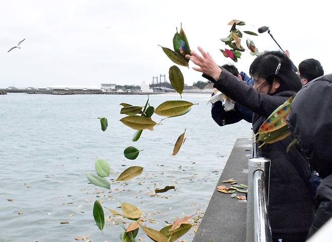 동일본 대지진으로 458명이 사망한 후쿠시마현 소우마시의 연안에서 지진 발생과 함께 이어진 쓰나미로 가족을 잃은 유족들이 "잊지 않을께요" 등의 추도 문구가 적힌 목련잎을 바다에 흘려 보내고 있다. [지지통신]