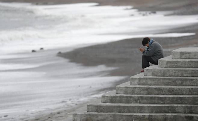 11일 일본 후쿠시마현 이와키의 해변에서 한 여성이 지진 피해 희생자들을 애도하면서 바다를 향해 기도를 하고 있다. [로이터=연합뉴스]