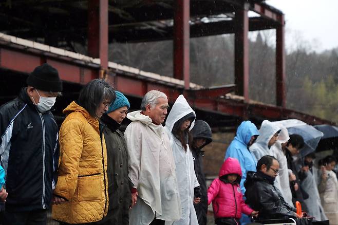 일본 이와테현에서 11일 지진 발생 시각에 맞춰 지진 피해로 가족을 잃은 유족들이 묵념을 하고 있다. [지지통신]
