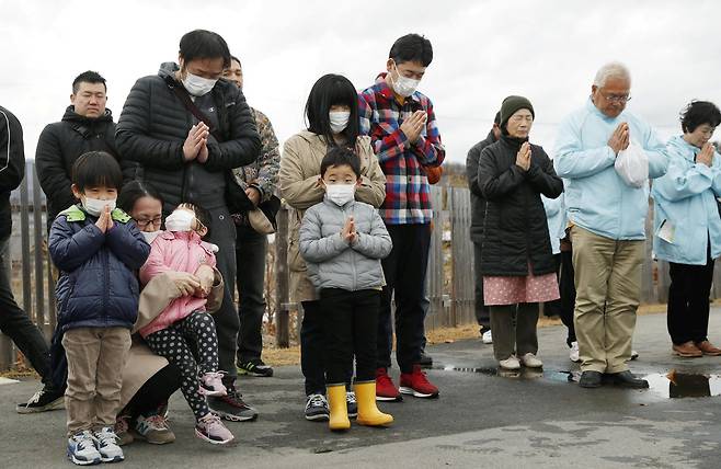 10일 후쿠시마현 이와키에서 시민들이 묵념을 하고 있다. 지진 발생 당시 어머니 뱃속에 있었을 나이의 아이들도 함께 묵념을 하고 있다. [로이터=연합뉴스]