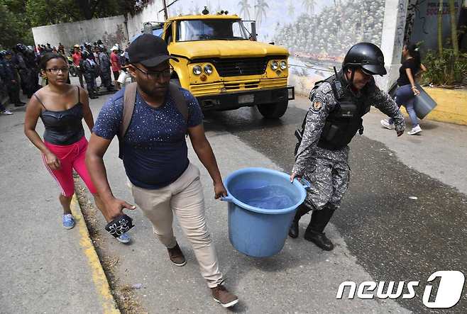 물을 길어 나르고 있는 베네수엘라 시민과 군병력. © AFP=뉴스1