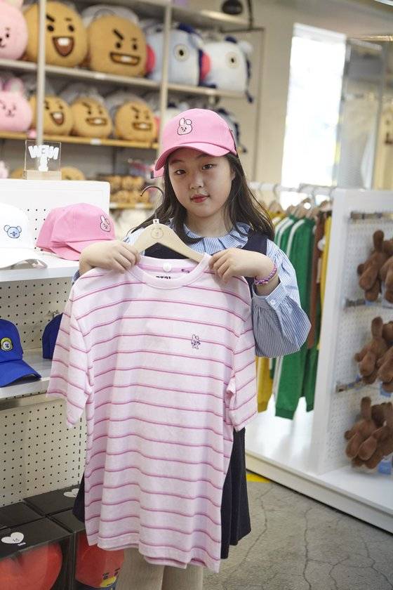 맹서후 학생기자가 BT21 캐릭터 '쿠키'가 있는 모자를 쓰고 티셔츠를 들어 보였다. 잘 만든 굿즈 하나는 다양한 형태로 퍼져 나간다.