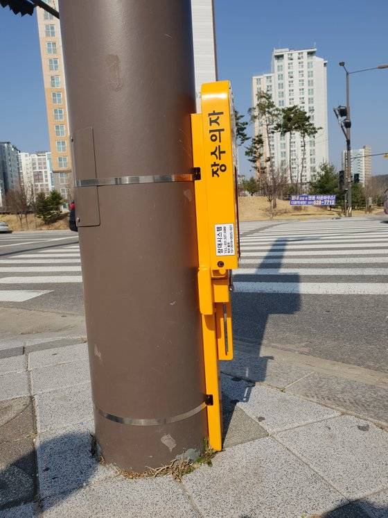 장수의자는 신호등 기둥 등에 접이식으로 매달려 보행자의 보행을 방해하지 않는다. ［사진 별내파출소］
