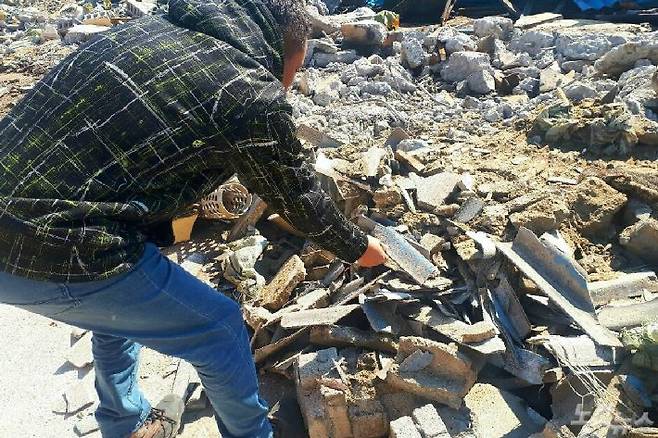 한 주민이 양어장 철거장에서 발견한 석면을 들어 보여주고 있다.(사진=유선희 기자)