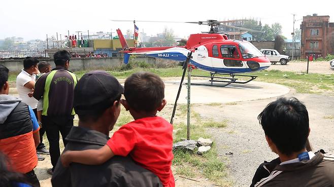 14일(현지시간) 네팔 에베레스트산 관문 루클라의 텐징-힐러리 공항에서 서미트항공 소속 소형비행기가 이륙 도중 주기된 헬리콥터와 충돌했다. 현지 주민들이 희생자를 이송하는 헬기를 바라보고 있다. [신화=연합뉴스]