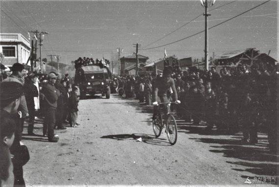 제43회 3.1절을 기념해 울산에서 열린 사이클 대회에서 대회진행자와 기자로 보이는 사람들이 소형트럭을 타고 선수를 뒤쫓고 있다. 포장되지 않은 흙길은 사이클로크로스(cyclo-cross) 또는 파리-루베(Paris-Roubaix)를 연상시키기도 한다./사진=울산시 제공