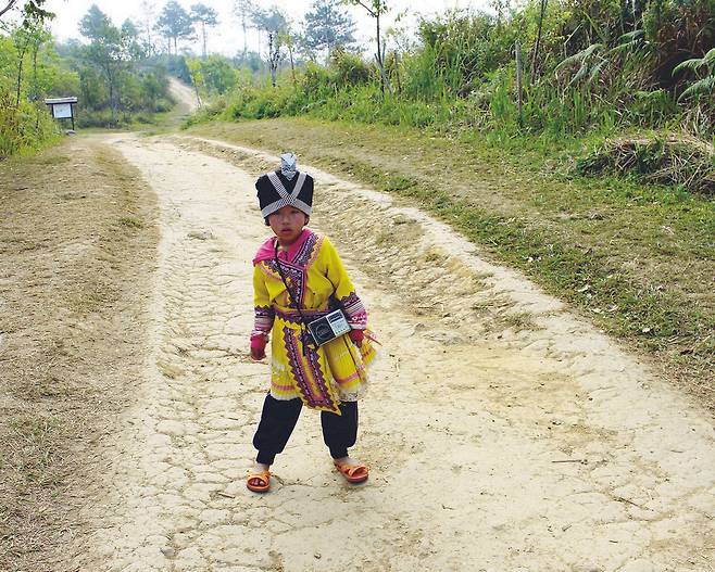 태국 고산족 어린이가 등산로 중앙에 서서 몸을 흔드는 춤을 추고 있다.