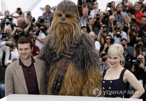 2018년 5월 15일(현지시간) 프랑스 칸 영화제 행사장에서 미국 배우 엘든 이렌리치(왼쪽)와 영국 배우 에밀리아 클라크(오른쪽)가 스타워즈의 캐릭터 '츄바카'(가운데)와 기념 사진을 촬영에 응하고 있다.[EPA=연합뉴스]