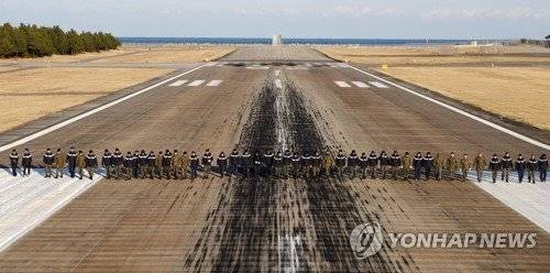공군 비행장에서 병사들이 일렬로 걸으며 활주로 이물질을 확인하고 있다. [연합뉴스]