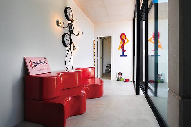 침실로 향하는 복도. 뒤뜰 중앙이 내려다보이는 편안한 공간이다. 아르키줌 그룹이 1966년에 디자인한 소파 위에 실비 플뢰리(Sylvie Fleury)의 스크린 프린트 작품이 놓여 있다. 벽에 걸린 설치미술 작품은 매튜 맥카슬린(Matthew McCaslin)이 제작. 뒤쪽 바닥에는 기욤 파리(Guillaume Paris)의 그림과 마티외 메르시에의 ‘해머 앤 캡’이 놓여 있다.