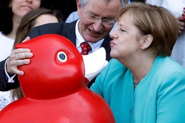 앙겔라랄 메르켈 독일 총리가 23일(현지시간) 독일 로스토크에 있는  바이오테크 센토진AG를 방문해 대형 빨간 오리 인형을 선물 받고 있다. 로이터 연합뉴스