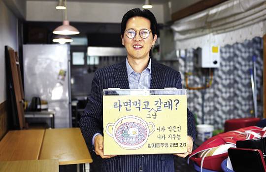 박광리 우리는교회 목사가 28일 교회 앞 양지동 주방에서 ‘라면 먹고 갈래’라는 팻말을 들고 있다.