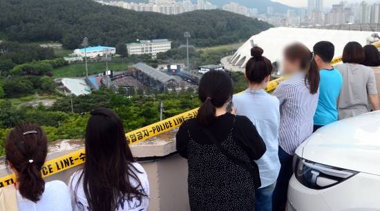 지난 15일 열린 방탄소년단(BTS)의 다섯 번째 팬미팅 장소인 부산 아시아드보조경기장 인근 고지대에서 팬과 시민 등이 공연장을 내려다 보고 있다. 뉴시스