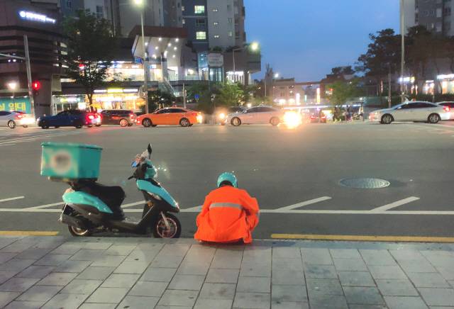 비 예보가 있었던 지난 주말 서울 합정역 인근. 후텁지근한 날씨에 비옷까지 걸쳐입은 배달 라이더가 보도에 앉아 잠시 쉬고 있다. / 강신우 기자