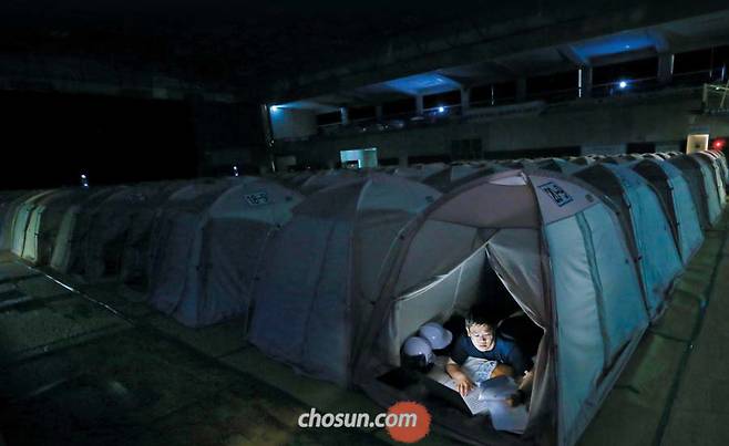 지난달 24일 오후 11시 경북 포항시 북구 흥해실내체육관 지진 이재민 대피소에서 본지 기자가 취재 자료를 정리하고 있다. 오후 10시 대피소의 불이 꺼지면 이재민들은 3.15㎡(0.9평) 텐트로 들어가 잠을 청한다. 2층 텐트를 잡았던 기자는 더위를 참지 못하고 에어컨 바람이 통하는 1층으로 내려왔다. /오종찬 기자