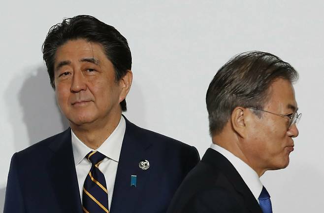 지난 6월28일 오사카에서 열린 주요 20개국(G20) 정상회의에 참석한 문재인 대통령이 아베 신조 일본 총리와 악수한 뒤 그를 지나쳐 걸어가고 있다. 아베 총리의 시선이 카메라를 보고 있다.  오사카 | AP연합뉴스
