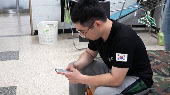 국방부는 지난 4월부터 일과 후 휴대폰 사용을 허용했다. 현장에선 이런 조치에 만족감을 드러냈다. 조리병은 정리 업무를 마친 뒤 휴대폰을 받기 때문에 사용 시간은 짧다. 정민구 상병이 생활관에서 휴대폰을 사용하고 있다. [영상캡처 = 왕준열 기자]