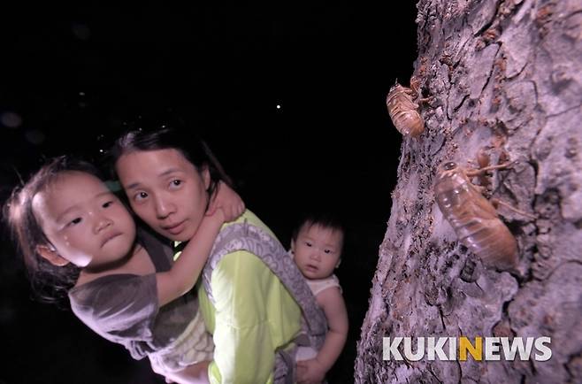 아이들과 서울숲에 산책나온 가족이 매미 유충이 나무에 기어오르는 모습을 신기한 듯 바라보고 있다.