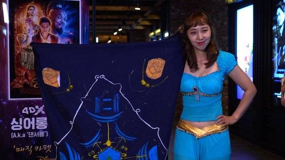 자스민 공주 분장을 하고 '알라딘' 4DX 댄서롱 상영을 찾은 관객, 그리고 양탄자. 극중 마법 양탄자를 코스프레한 것으로 실제 천 안에 사람이 들어가있다. [사진 CJ CGV]