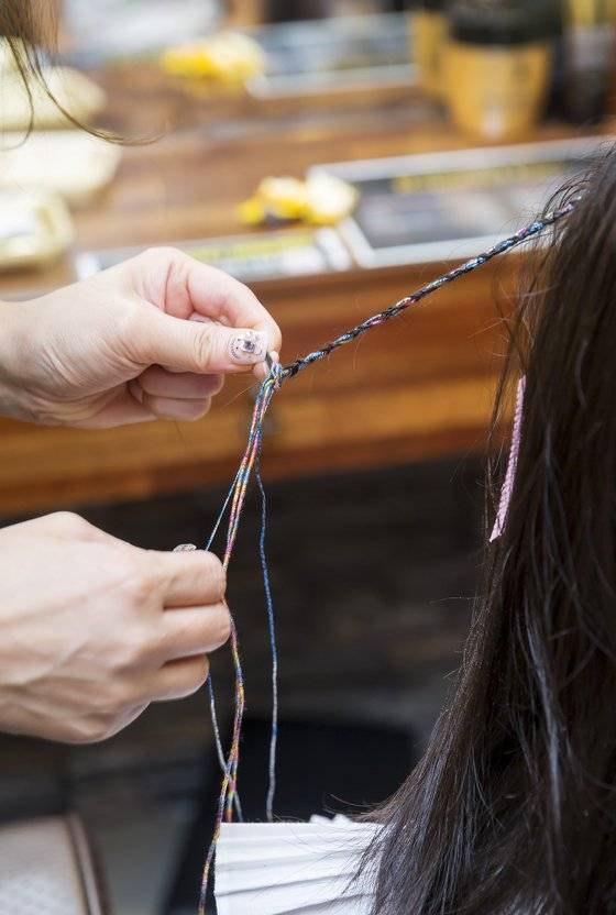 머리카락과 실을 같이 땋는 얀 블레이즈 시술을 하는 모습.
