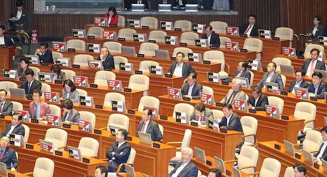 조국 법무부 장관이 26일 오후 국회 본회의장에서 열린 정치 분야 대정부질문에 참석하자 자유한국당 의원들이 '조국 사퇴'등이 적힌 손팻말을 붙이고 있다. 신소영 기자 viator@hani.co.kr