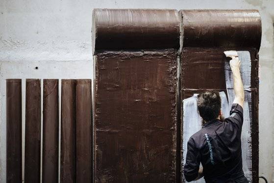 프랑스 초콜릿 제조사 패트릭로저 소속 예술가가 다크초콜릿과 화이트초콜릿으로 베를린장벽을 재현하고 있다. [AP=연합뉴스]