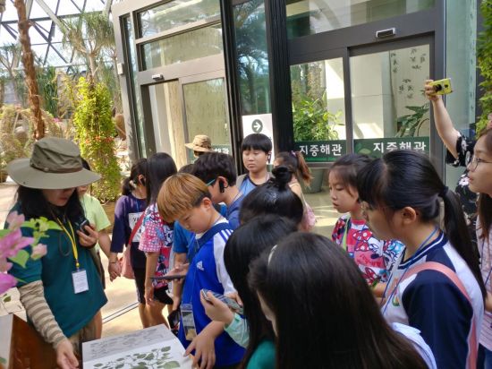 서울식물원의 온실 '지중해관'을 찾은 학생들이 투어프로그램 도중 해설사의 설명에 귀기울이고 있다. / 서울식물원 제공
　