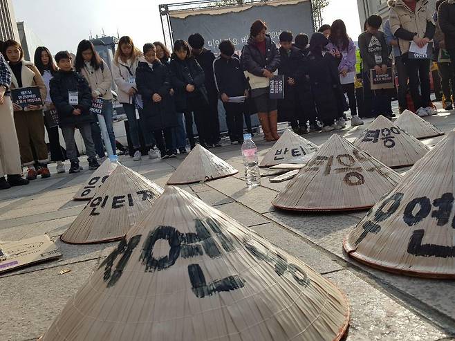 23일 서울 중구 파이낸스센터 앞에서 열린 ‘베트남 민간인 학살, 이제는 국가의 책임을 묻습니다’ 문화제 참가자들이 바닥에 놓인 ‘넌라’에 쓰여진 베트남전 민간인 학살 피해자 이름을 향해 묵념하고 있다.