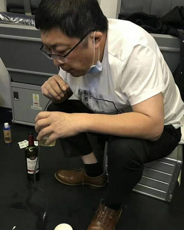 중국 의사 장훙이 지난달 19일 새벽 비행기 안에서 스스로 소변을 보지 못해 방광이 터질 위험에 처한 노인의 소변을 직접 빨대로 빨아내 뱉어내고 있다. 신민망.