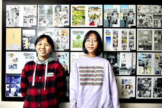 홍예린·은다민 학생기자가 다양한 만화가 전시된 벽면을 배경으로 포즈를 취했다.