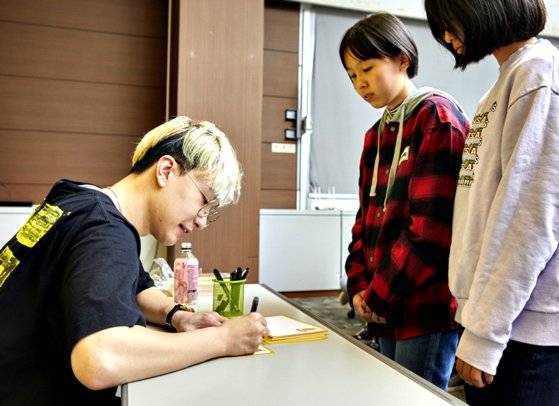 와나나 작가가 학생기자단에게 줄 글귀를 적고 있다.