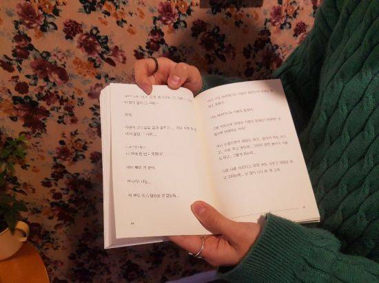 이 작가는 "요즘은 내가 한 말을 남들이 얼마나 들어주는 지가 힘인 것 같다"고 했다. 그는 "고인이 된 구하라씨가 '힘들다, 그만해달라' 계속 말했고 구 씨의 이야기에 진정으로 귀 기울이고 공감했다면 그런 댓글을 달지 않았을 것"이라며 "세상이 너무 커지고 사람들도 많아졌다. 서로의 이야기를 들을 수 없게 되다 보니 잠시 여유를 갖고 다른 사람의 이야기를 들어주는 행위가 더 중요해졌다"고 했다. 이 작가 자신이 쓴 '장롱다방' 일부를 펼쳐 보이고 있다.