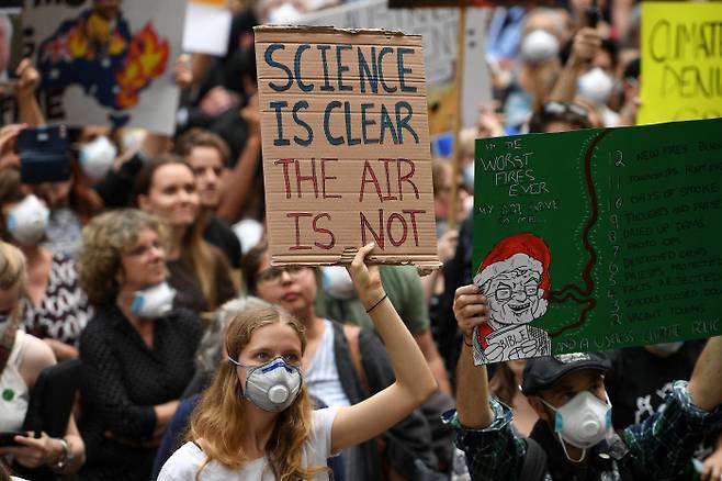 11일(현지시간) 호주 시드니 시청 주변에 모인 시민들이 마스크를 쓴 채로 정부가 기후변화를 증명하는 과학적 근거들을 외면하고 있다는 손팻말을 들고 있다. 시드니|로이터연합뉴스