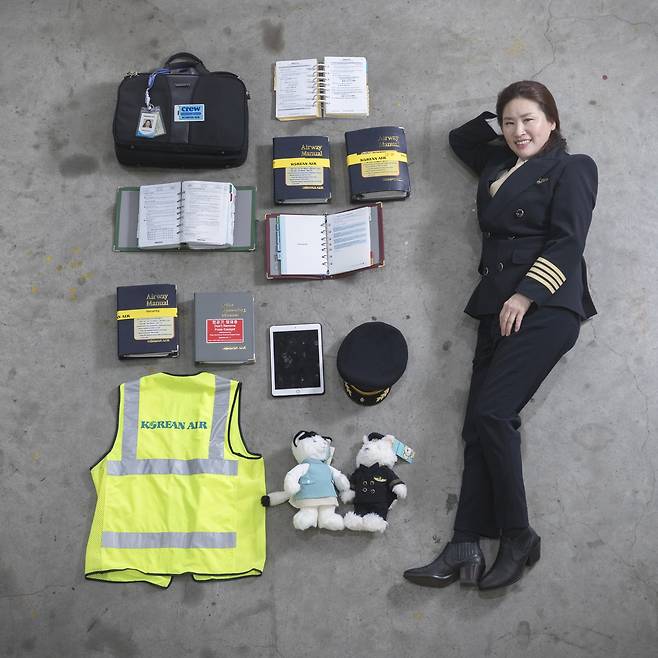 신수진 대한항공 기장은 지난 2008년 국내 민항 최초로 여성 기장이 되었다. 신 기장이 인천 영종도 대한항공 격납고에서 비행에 사용하는 물품들과 누웠다. 종이책 형태의 매뉴얼북은 현재 태블릿 pc로 대체됐다. 장진영 기자