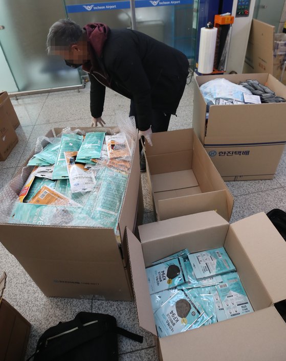 5일 오전 인천국제공항 1터미널에서 공항 이용객들이 중국으로 가져갈 마스크를 마스크 상자에서 택배회사 상자로 옮겨 담고 있다. [연합뉴스]