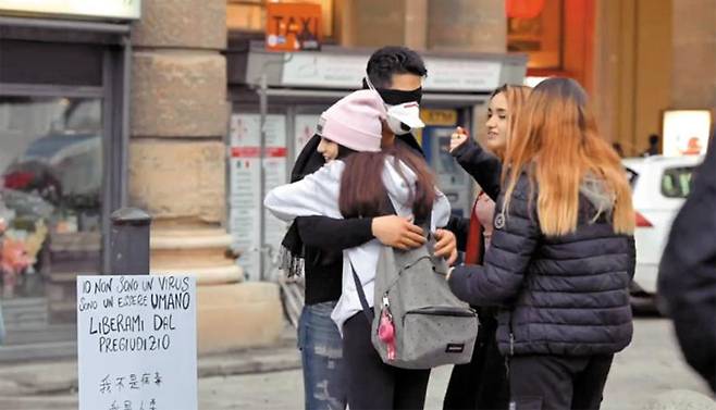 “나는 바이러스가 아니다”… 중국계 이탈리아인의 프리 허그 - 중국계 이탈리아인 마시밀리아노 마르틸리 장이 2일(현지 시각) 이탈리아 피렌체에서 마스크를 쓰고 눈을 가린 채 사람들과 ‘프리 허그’를 하고 있다. 그의 옆에는 이탈리아어·중국어·영어로 쓴 ‘나는 바이러스가 아니다. 나는 인간이다’란 팻말이 놓여 있다. 그는 신종 코로나바이러스 감염증(우한 폐렴)으로 중국인 등 아시아인에 대한 혐오 정서가 늘자 이 같은 퍼포먼스를 준비했다고 한다. /UGIC(중국계이탈리아인청년단체) 페이스북